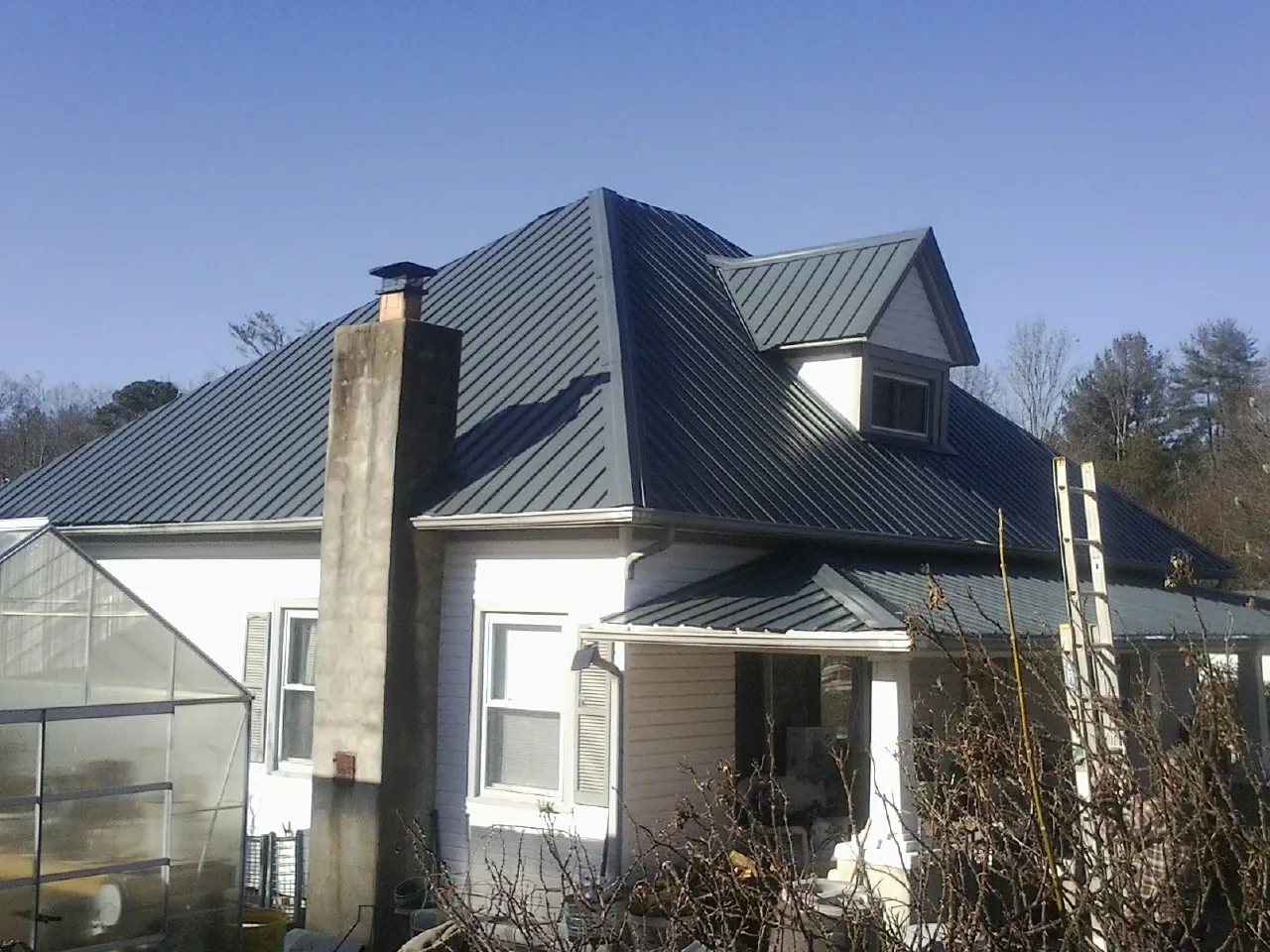 Dark blue standing seam metal roof on a white farmhouse with dormer — Slate & Tile Roof Repair by Roofing Brothers in Livingston Manor