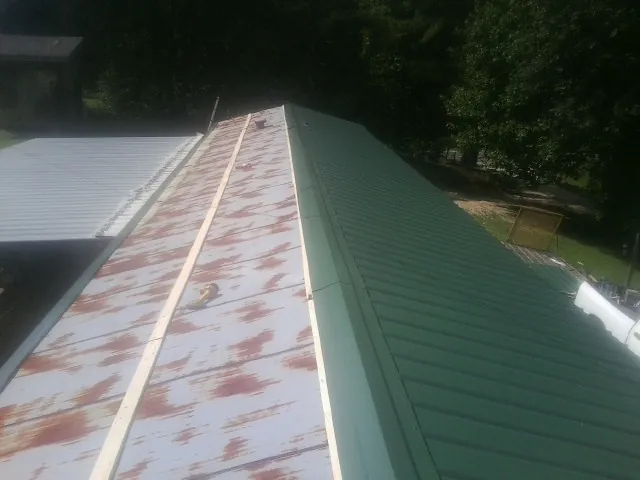 Old rusted panels beside newly installed green metal roofing — Wind Damage Roof Repair by Roofing Brothers in Livingston Manor