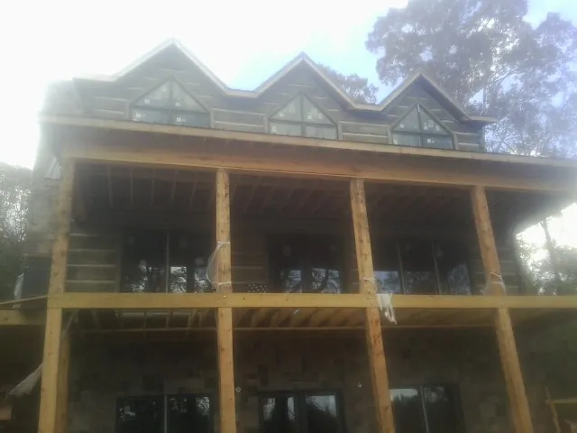 Dormers and porch framing on a large log home under construction — Roof Coating work by our crew in Livingston Manor