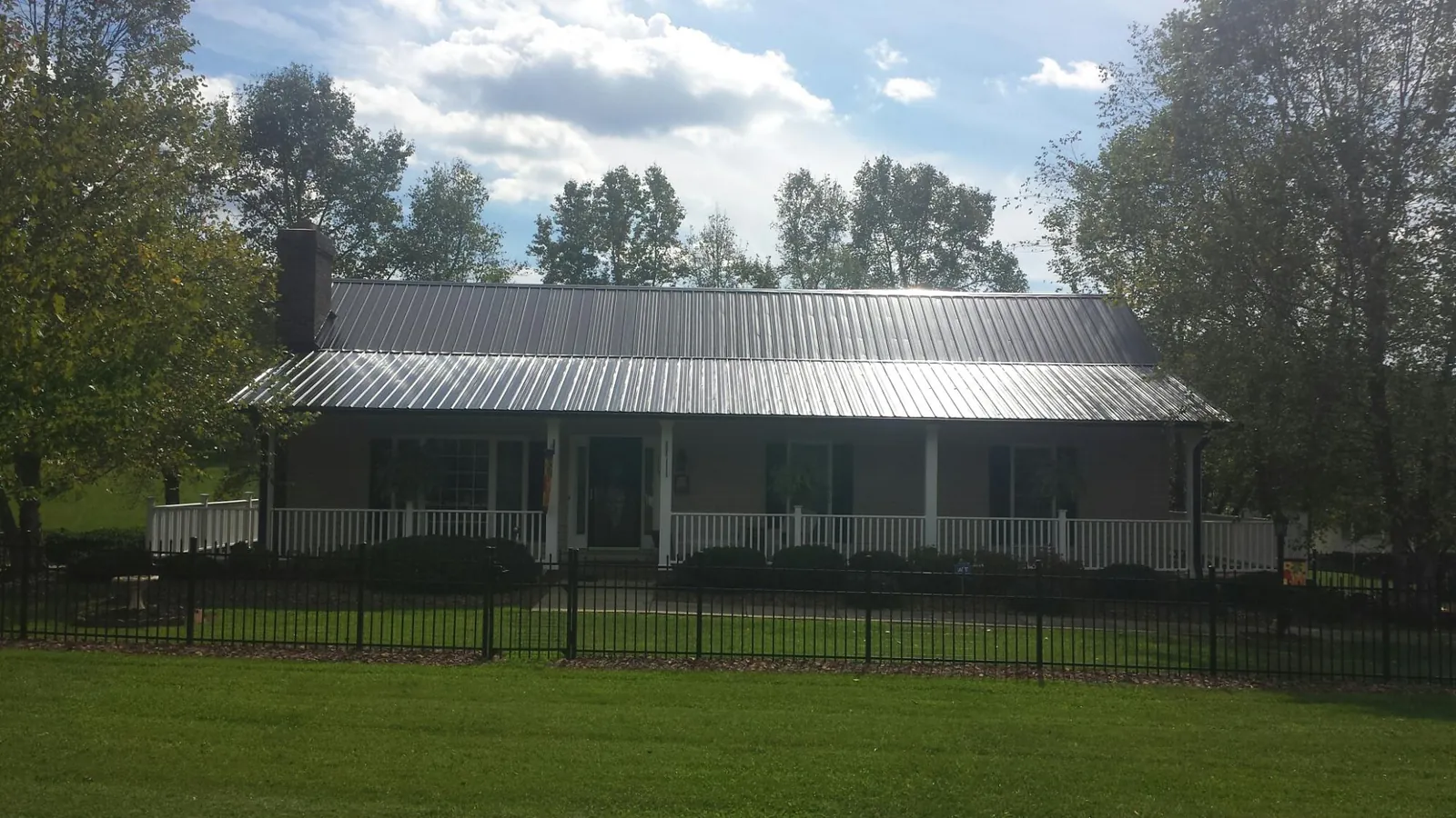 Gray metal roof on a brick ranch with a full width front porch — Gutter Guard Installation work by our crew in Livingston Manor