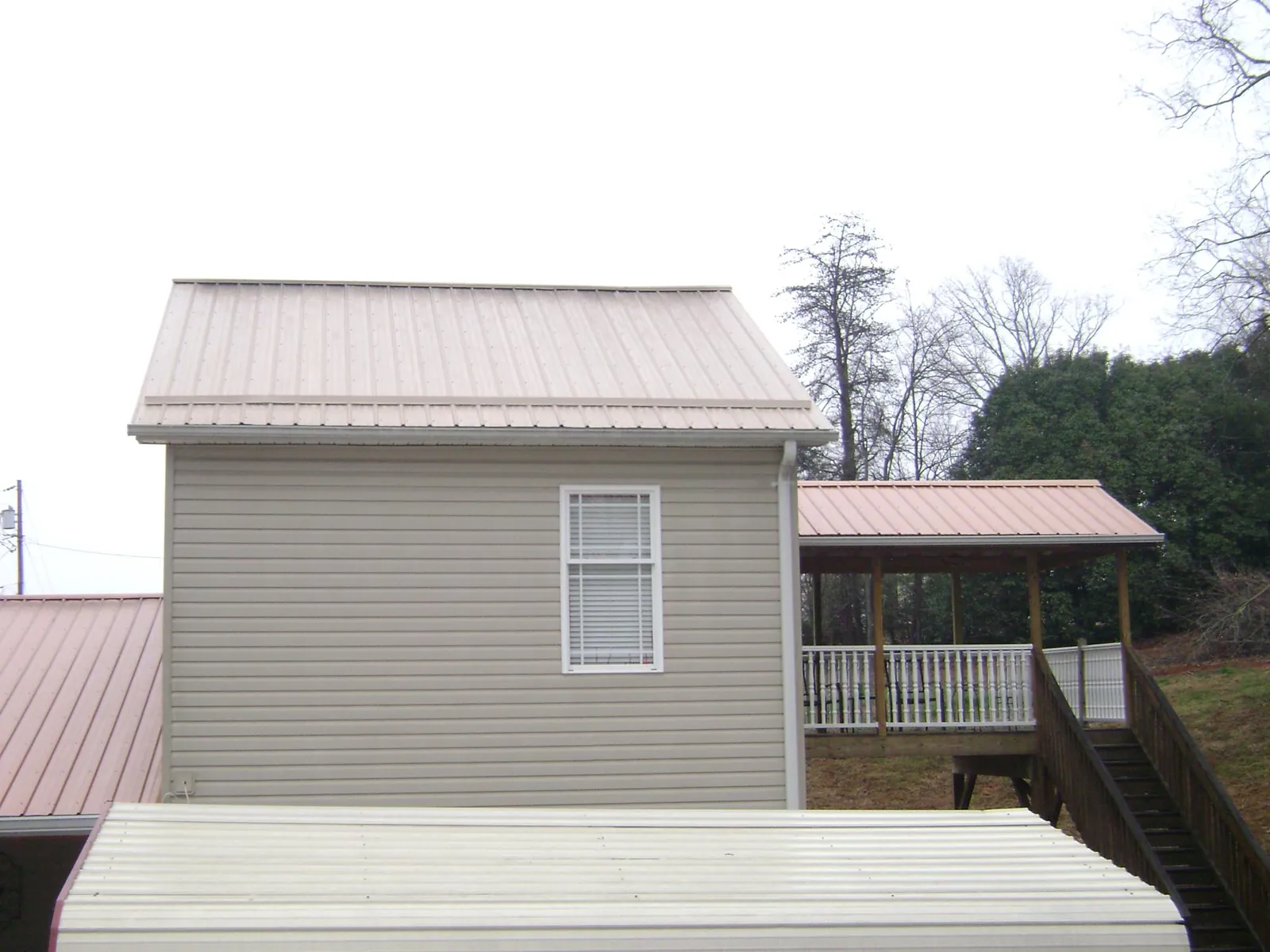 Tan metal roofs on a two story addition and attached porch, from a Roof Replacement job in Livingston Manor