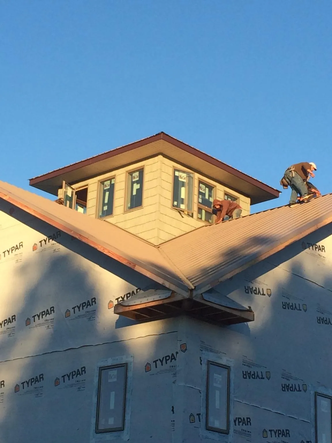 Roofers working around a rooftop cupola on a new metal roof at sunset — Roof Waterproofing in Livingston Manor by Roofing Brothers